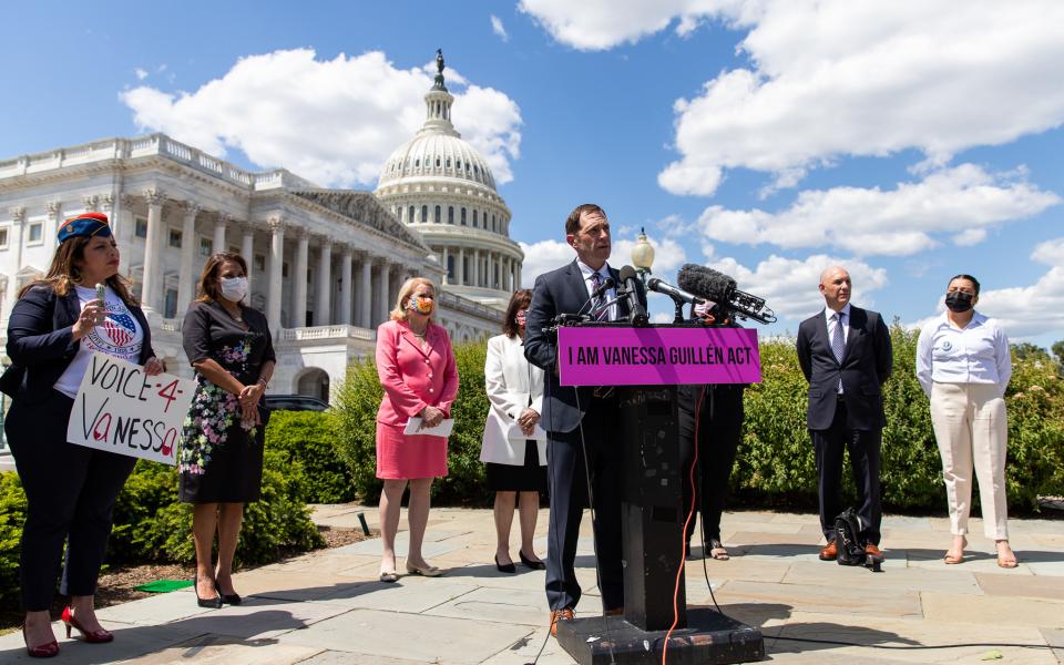 Rep. Jason Crow speaking at podium surrounded by members of congress and the Guillen family